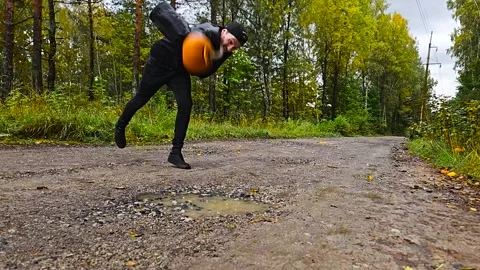 Man throwing and destroying a orange Halloween pumpkin in slow motion into Video stock 286423163