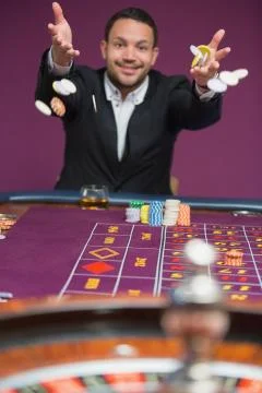 Man throwing chips onto roulette table Stock Photos