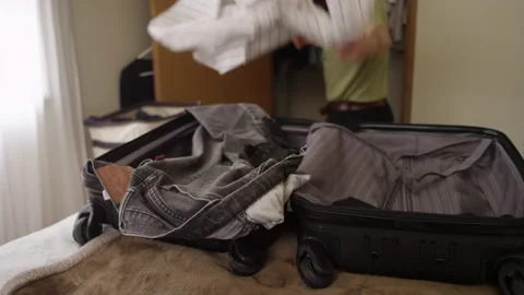 Man throwing clothes from his closet into a suitcase on the bed 動画素材 134283018