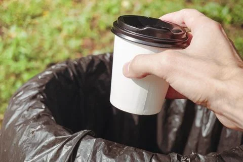 Man throwing coffee cup into bin outdoors 库存照片