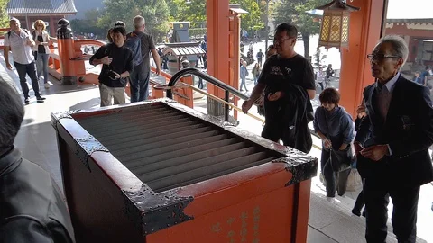 A man throwing coins on the wishing box in Senso-ji Tokyo Japan Stock Footage 129280625