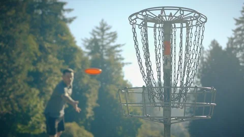 Man Throwing Disc into Basket at Frisbee Golf Course Stock Footage