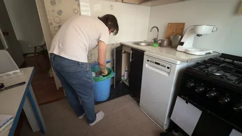 Man throwing garbage into trash bin in small kitchen, everyday household chore, Stock Footage 336980767