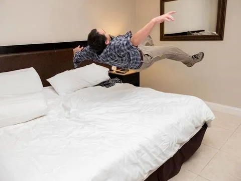 Man throwing himself into bed. Фото
