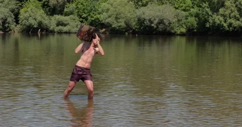 Man throwing a log in a river Stock Footage 244181023