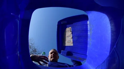 Man throwing plastic bottles into recycling wheelie bin united kingdom Stock Footage 125743172