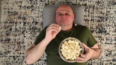 Man is throwing up popcorn and trying to catch it with his mouth Stock Footage 197662744