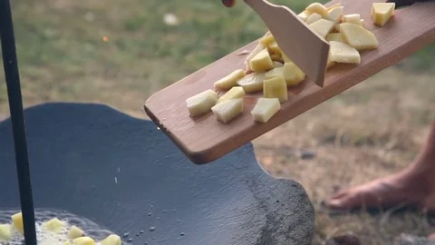 Man throwing the potatoes in a large heated pan Stockbeeldmateriaal 76195077