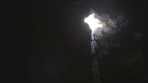 Man throwing off rescue rope to another in a deep mine Stock Footage 79796705