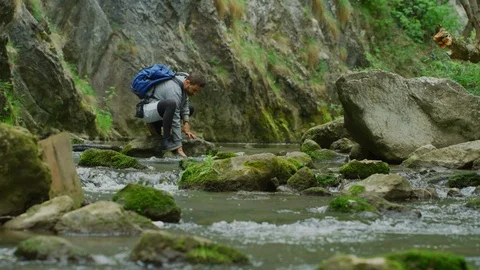 Man throwing rocks into a river Stock Footage 99963228