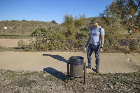 Man throwing trash into outdoor bin Stock Photos