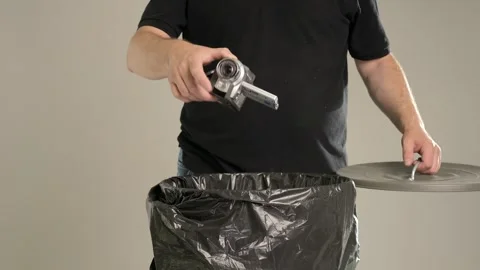 A man is throwing a very small outdated home camera into the trash bin Stock Footage 243639682