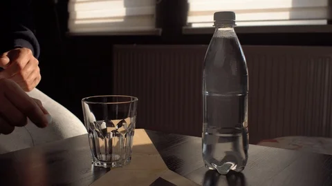 A man throws 2 hangover pills into a glass and fills them with water Stock Footage 119712430