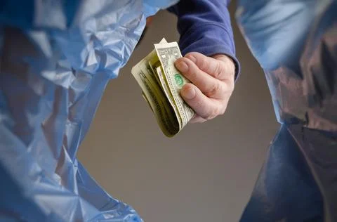 A man throws American dollars in the trash. A hand holds the cash over the tr Foto stock