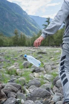 A man throws away a plastic bottle in the mountains. environmental pollutio.. Stock Photos