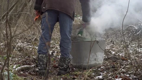 A man throws a bag of plastic bottles into the fire. A homeless man burns tra Stock Footage 147456240