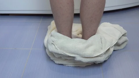 A man throws a bath towel on the floor and climbs into the bath. Rear view of Stock Footage 118721973