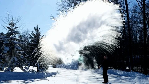 Man throws boiling water into minus 20 degree frigid winter air on sunny day. Stock Footage 102061874