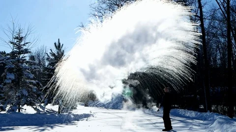 Man throws boiling water into minus 20 degree frigid winter air on sunny day. Stock Footage 102061890