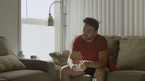 Man throws cellphone in couch, then picks up a book and enjoys it Stock Footage 114645604