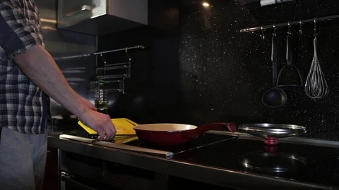 Man throws cheese from a cutting board into a frying pan Stock Footage 86156125