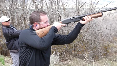 Man Throws Clay Disc In The Air For Another Man To Shoot Stockbeeldmateriaal 77317651