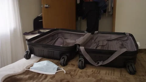 Man throws clothes from a closet into a suitcase laying on a bed 스톡 동영상 134283010