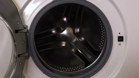 A man throws clothes into the washing machine in the room Stock Footage 261756039
