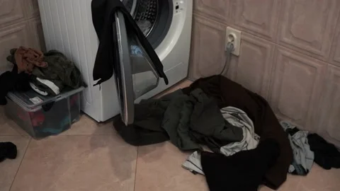 A man throws dirty things into the washing machine. Stock Footage 165213803