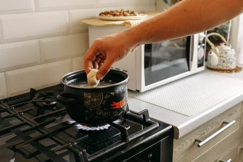 A man throws dumplings into a pot of boiling water. Cooking food. Stock Photos