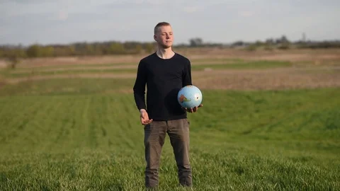 Man throws earth globe in green field Stock Footage 129082301