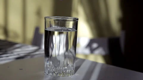 Man throws effervescent tablet into a glass of water at the table Stock Footage 104332939