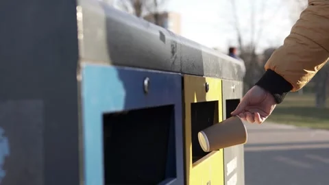 A man throws empty paper cups into a trash bin for recycling. Stock Footage 268187806