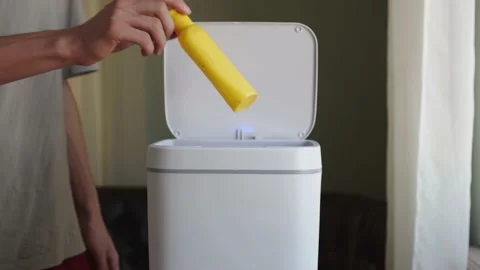 A man throws an empty plastic shampoo container into a household trash can Stock Footage 220913581