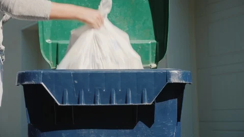 A man throws a garbage bag into a waste tank near his house Stock Footage 117668535