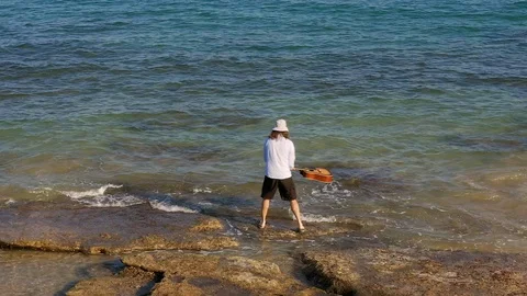 Man throws guitar in sea or ocean. Musician hippy grunge throws musical Vidéo 126768562