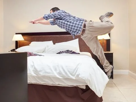 Man throws herself on the bed in the room to lie down. Stock Photos