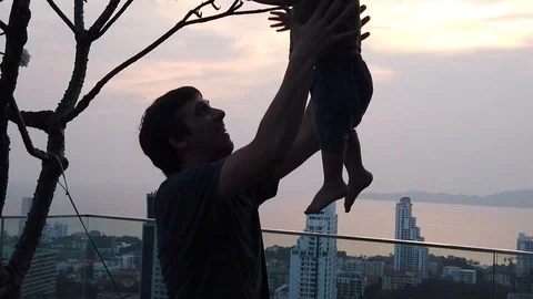 A man throws his two-year-old child into the air Stock Footage 104949951
