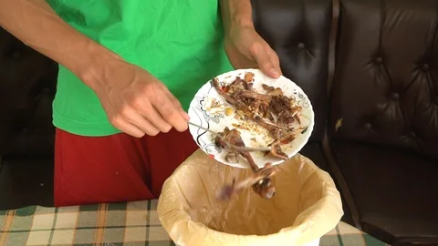 A man throws meat scraps and chicken bones into a bin Stock Footage 115761364