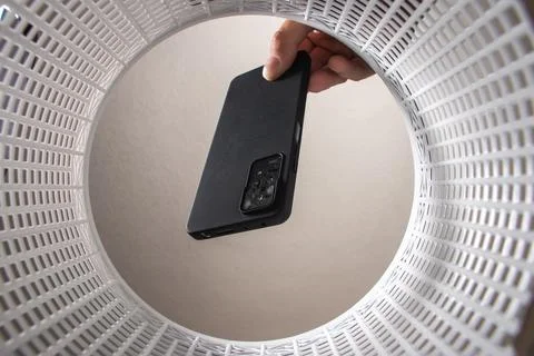 A man throws a non-working smartphone into a trash can. Bottom view from the  Stock Photos