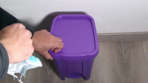 A man throws an old surgical mask into a trash can 스톡 동영상 153376435