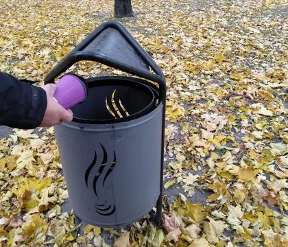 A man throws a paper cup in the trash. Stock Photos