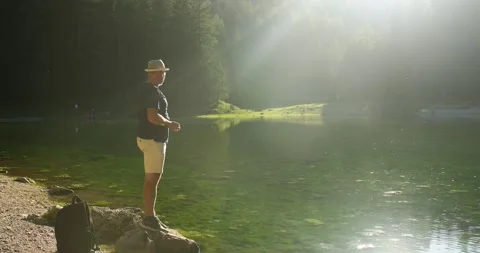 A man throws pebbles into the lake. Mountain landscape Stock Footage 246491824