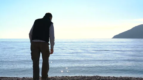 Man throws pebbles into the sea 動画素材 151716497