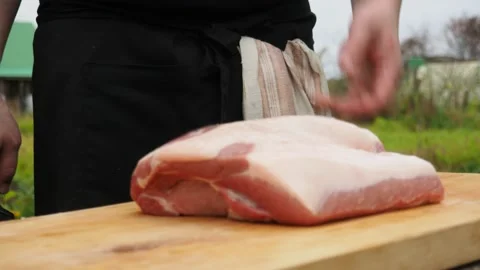 A man throws a piece of pork on a chopping Board. cutting meat into pieces Stock Footage 141455395