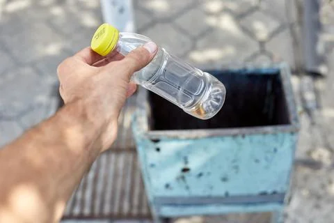 A man throws a plastic bottle into a trash can Stock Photos