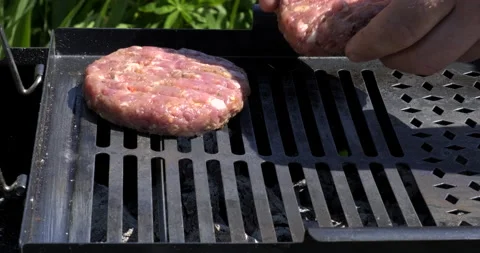 Man Throws Raw Cutlets for Burgers onto Hot Metal Grate. Grill Meat. Picnic Stock Footage 132336780
