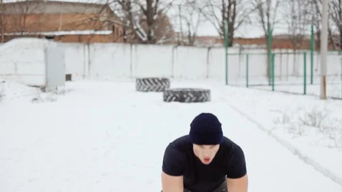 Man throws a rubber tire over himself, man doing crossfit exercises in winter Video stock 100303606