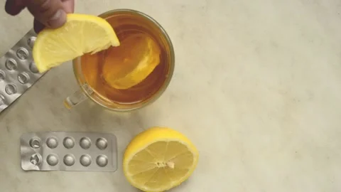 Man throws a slice of lemon into a cup of lemon tea on background of lemon and Video stock 218421980