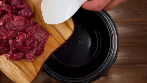 The man throws the sliced meat in the slow cooker with a spatula Stock Footage 129100921